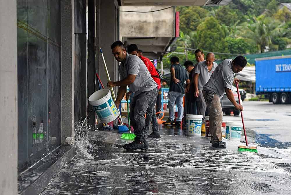 Pekerja kedai melakukan kerja-kerja pembersihan di premis berikutan terjejas akibat banjir berhampiran Pekan Lama Nilai pada Isnin. Foto Bernama