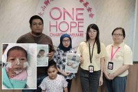 Mohd Faiz (kiri) dan isterinya, Norazlini menunjukkan gambar anak mereka ketika mendapatkan bantuan daripada One Hope Charity & Welfare.