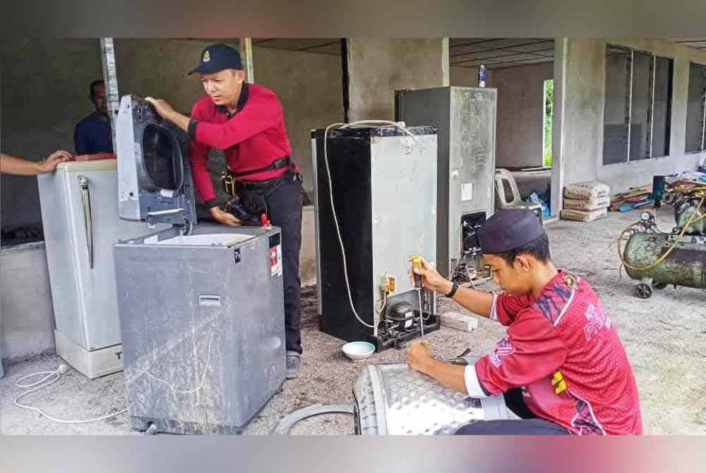 Anggota Jabatan Amal Pas membantu membaik pulih barangan elektrik milik mangsa banjir di Raub. Foto ihsan Jabatan Amal Pas Raub