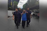 Tertuduh diiring polis ketika hadir ke Mahkamah Sesyen di Seremban pada Selasa.