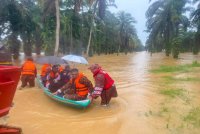 Anggota bomba membantu mangsa yang terperangkap dalam banjir di SK Padang Kubu. Foto BBP Cheneh