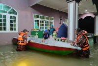 Anggota bomba membantu memindahkan mangsa banjir selepas kediaman mereka dinaiki air secara mendadak.