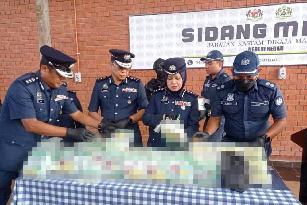 Nor Izah (dua dari kanan) memeriksa beberapa bungkusan berlabel teh cina yang di dalamnya dipercayai mengandungi dadah jenis methamphetamine pada sidang media di Pejabat Penguatkuasaan JKDM Bukit Kayu Hitam pada Rabu.