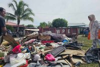 Rashidah (kanan) membantu mengasingkan barangan sambil mencari dompetnya yang ditenggelami banjir di Kampung Tanjung Tin, Kampar.