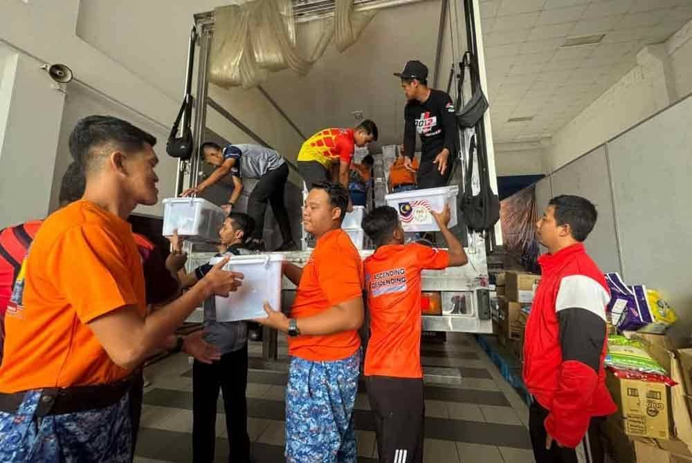 Anggota APM membantu mengangkat kit bantuan bencana yang diterima daripada Nadma.