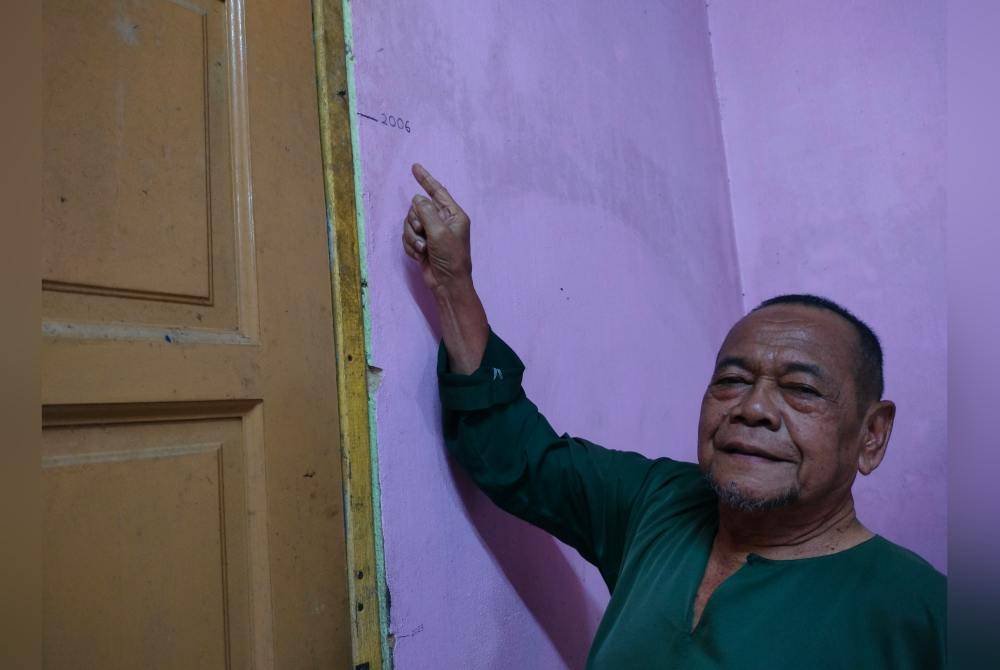 Ramin menunjukkan paras air banjir di pintu rumahnya di Kampung Seri Gambut, Pekan Nanas di Pontian.