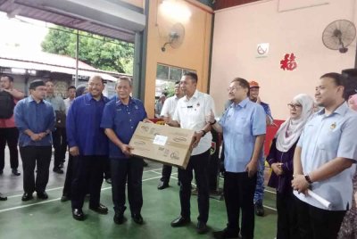 Aminuddin (tiga dari kiri) ketika menyampaikan sumbangan kepada mangsa banjir di Dewan Besar Dangi pada Isnin.