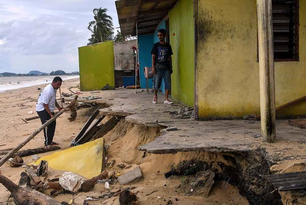 Mohd Lokman (kanan) bersama Hasmizi (kiri) melihat struktur sebahagian kediaman yang runtuh dibadai ombak besar ketika tinjauan Bernama di Kampung Dalam Rhu, Pachakang, pada Rabu. Foto Bernama