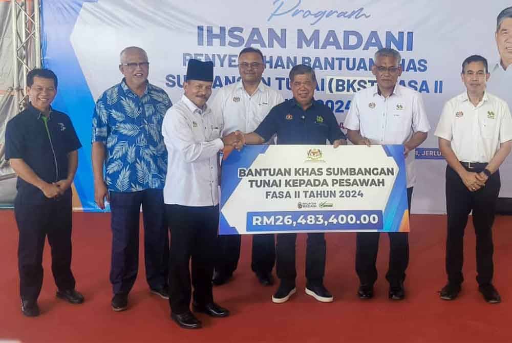 Mohamad (tiga kanan) menyerahkan BKST Fasa 2 Tahun 2024 pada Program Ihsan MADANI di pekarangan Pejabat Pertubuharn Peladang Kawasan (PPK) MADA F-II Jerlun pada Khamis.