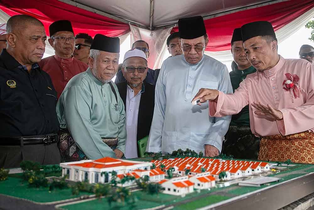 Anwar melihat pelan Cadangan Pembangunan Pusat Pengajian Islam At-Taiyibin ketika hadir pada Kenduri Rakyat dan Ziarah Mahabbah Ke Pusat Pengajian At-Taiyibin Tanah Hitam di Ipoh pada Jumaat. Foto Bernama