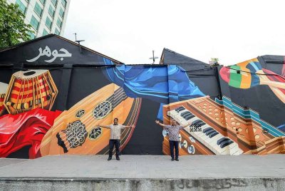 Raven (kiri) bersama Sharil Nizam bergambar di hadapan mural di Jalan Tan Hiok Nee. Foto Benama