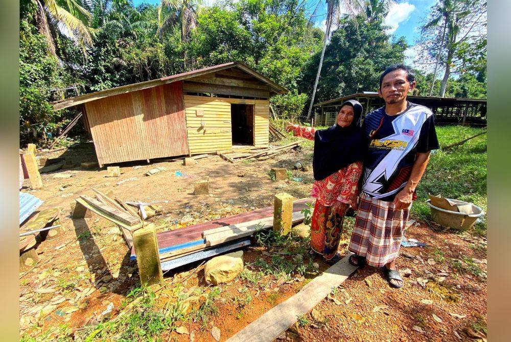 Fatimah bersama anaknya, Fauzi menunjukkan rumah mereka yang dihanyutkan banjir pada 26 November lalu.