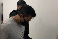 Tertuduh diiringi polis di mahkamah pada Ahad.