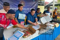 Nik Yusaimi (empat dari kiri) dan kakitangan KDN mengumpulkan al-Quran rosak akibat banjir. Foto SINAR HARIAN-ADILA SHARINNI WAHID.