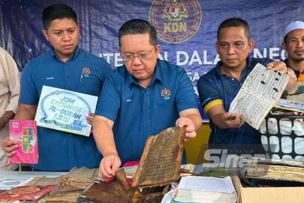 Nik Yusaimi (tengah) membelek helaian al-Quran yang rosak terkena bah. Foto SINAR HARIAN-ADILA SHARINNI WAHID