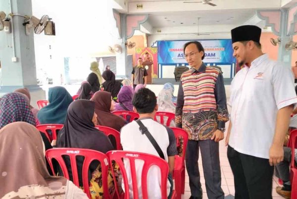 Ahmad Azrin (kiri) bersama Ilyas Helmi (kanan) beramah mesra dengan penerima bantuan pada Program Bantuan Makanan MAIDAM pada Ahad