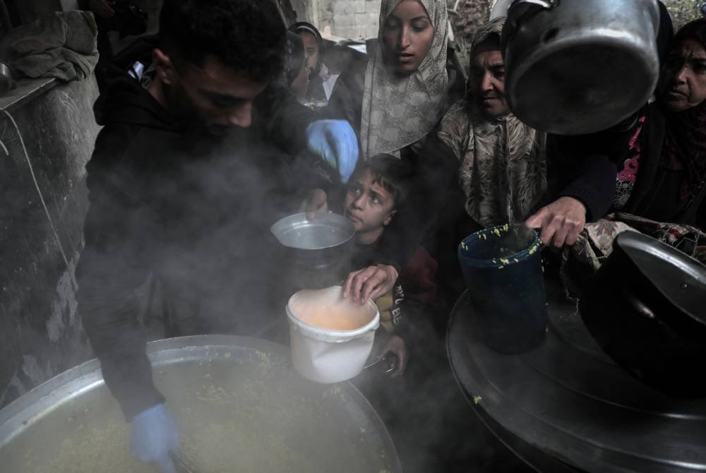 Orang ramai menerima bantuan makanan di pusat pengedaran makanan di bandar Deir al-Balah, tengah Semenanjung Gaza. Foto Xinhua