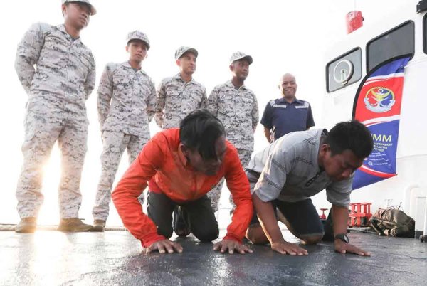 Nor Hasrul (kiri) dan Muhamad Ikmal sujud syukur di atas kapal KM Burau milik Agensi Penguatkuasaan Maritim Malaysia (Maritim Malaysia) Pulau Pinang selepas mereka berdua diselamatkan.