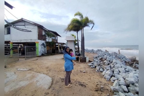 Nor Suhana menunjukkan benteng berbatu yang dibina sejak empat tahun lalu bagi mengelak chaletnya musnah akibat fenomena hakisan pantai.