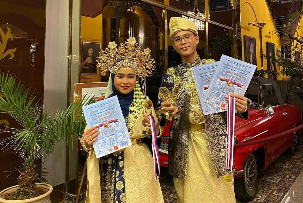 Nur Syafawati Damia dan Nik Muhamad Firdaus Putra bersama sijil penghargaan dan trofi yang dimenangi mereka.