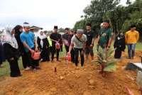 Mohamad Noorzuhairi menyiram air ke tanah perkuburan arwah bapanya setelah urusan pengebumian selesai. Foto Bernama