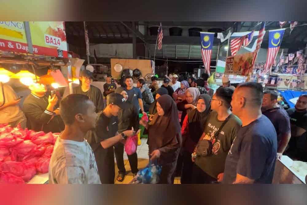 Orang ramai beratur untuk mendapatkan ayam percuma diagihkan di Pasar Chabang Tiga, pada malam Selasa.