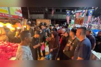 Orang ramai beratur untuk mendapatkan ayam percuma diagihkan di Pasar Chabang Tiga, pada malam Selasa.