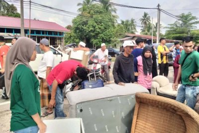 Nur Ain Suhada (kiri) melihat orang ramai beratur mendapatkan perabot terpakai.