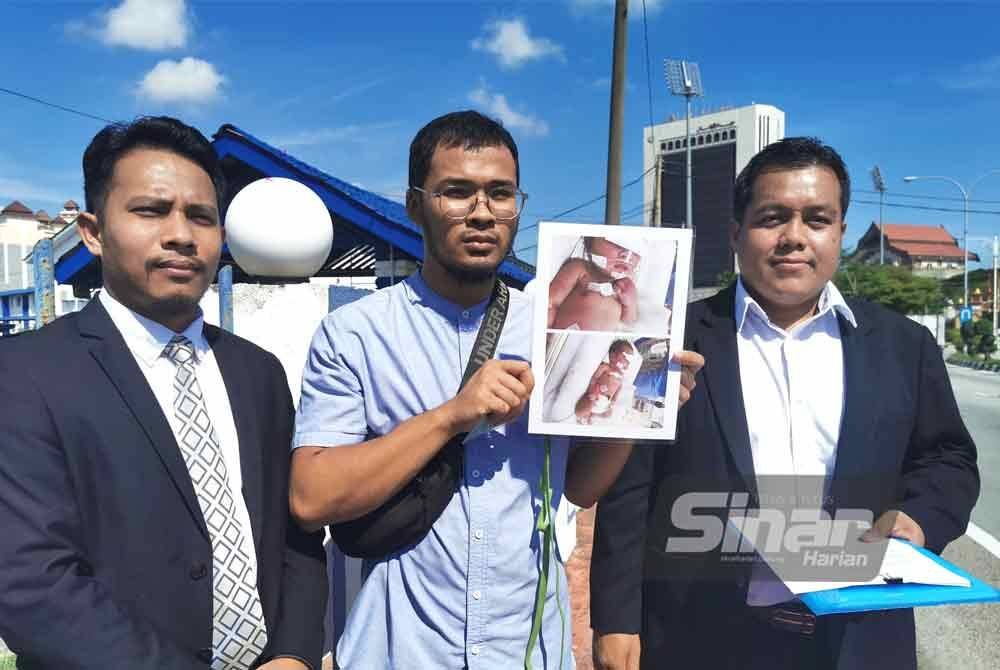 Muhammad Syarifuddin (tengah) di samping Mohd Hazwan (kanan) memegang gambar bayinya bersama laporan polis ketika ditemui di IPD Kuala Terengganu pada Khamis.