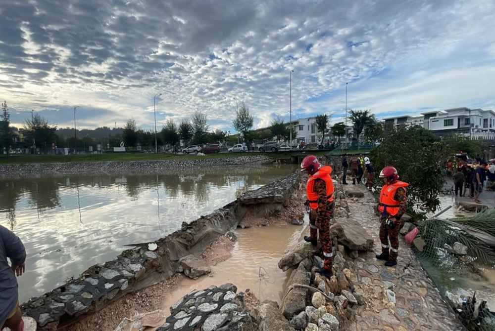 Anggota bomba melakukan pemeriksaan di lokasi kejadian banjir di Taman Sri Alam, Puncak Alam, Selangor selepas benteng takungan air pecah pada Ahad. - Foto:JBPM.