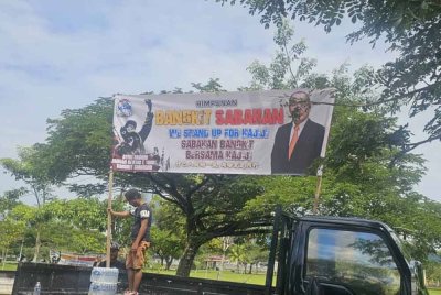 Kumpulan perhimpunan memasang kain rentang di atas lori di Anjung Selera, Likas, Kota Kinabalu.