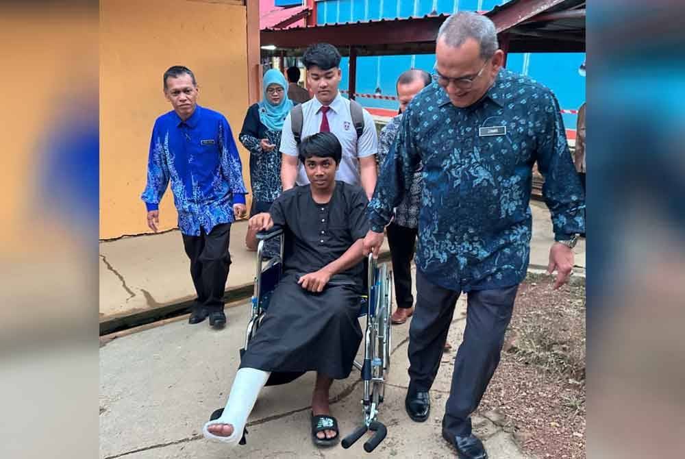 Mohd Zamri (kanan) turut membantu menarik Mohd Adam (tengah) yang berkerusi roda ke dewan peperiksaan. FOTO SINAR HARIAN-ADILA SHARINNI WAHID.