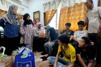 Kalsom (tiga, kiri) dan Tuminah (dua, kiri) menyantuni enam beradik yang merupakan anak yatim piatu di rumah mereka di Pekan Tangga Batu pada Jumaat. Foto Bernama