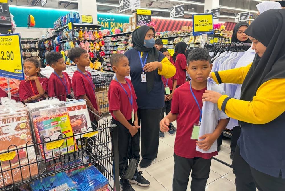 Murid Orang Asli yang beratur untuk mencuba pakaian sekolah masing-masing.