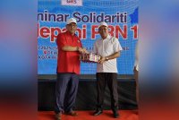 Japlin (kiri) menyampaikan cenderahati kepada Nizam (kanan) ketika hadir pada majlis Seminar Solidariti Mendepan PRN17 di Dewan Terbuka Datuk Japlin, Kota Belud.