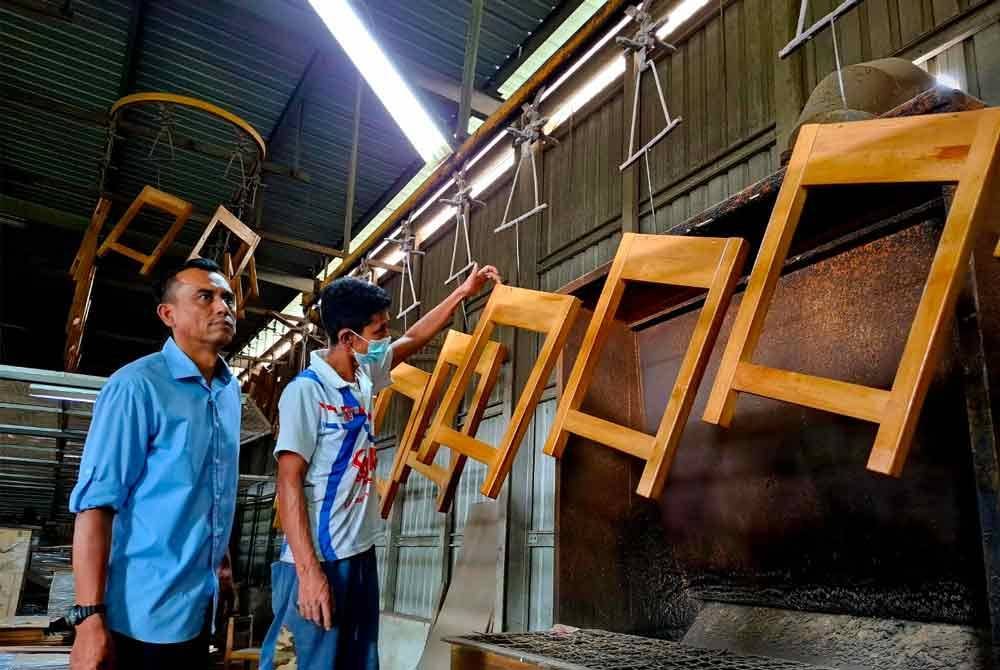 Mustafar menunjukkan proses pembuatan perabot kerusi dan meja untuk kegunaan sekolah yang dikeluarkan syarikatnya.