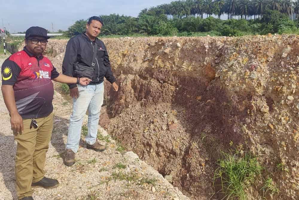 Amin Yaziz (kiri) menunjukkan runtuhan tembok konkrit yang runtuh hanya ditimbus dengan timbunan tanah oleh pihak berwajib.