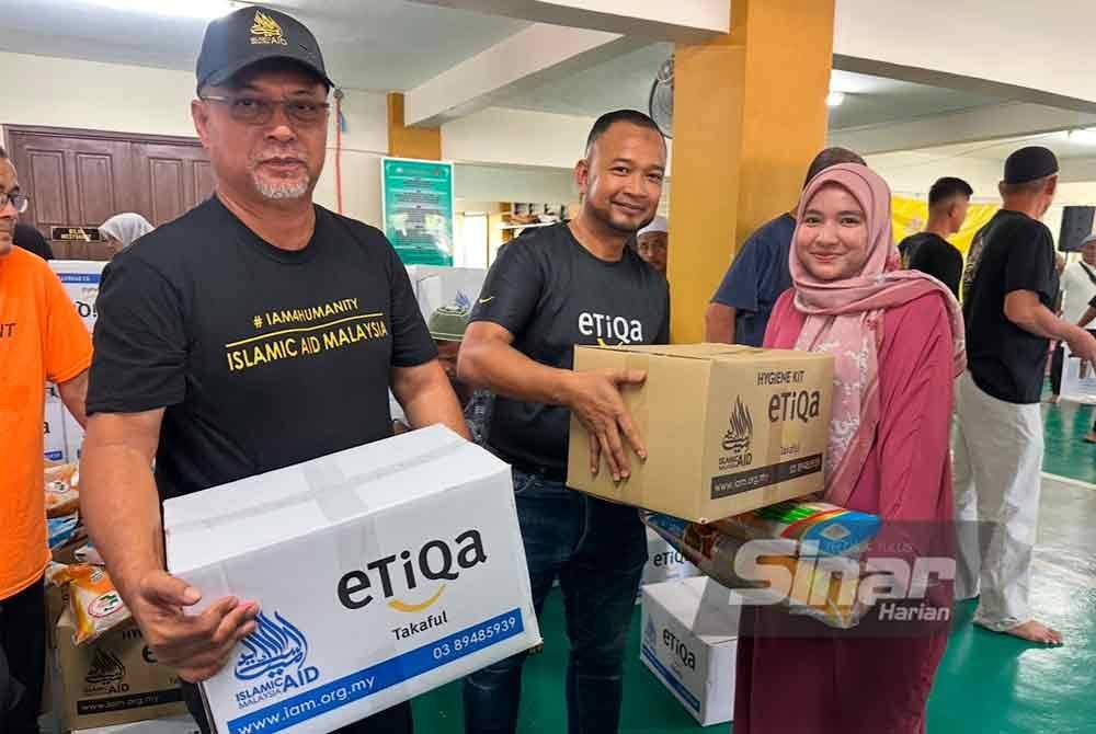 Muhamad Nurawi (tengah) diiringi Zawahir (kanan) menyampaikan beras kepada mangsa banjir. FOTO SINAR HARIAN-ADILA SHARINNI WAHID.