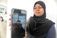 Nur Aliya Myzara, menunjukkan gambar kedua ubu bapanya yang disimpan di dalam telefon bimbit.