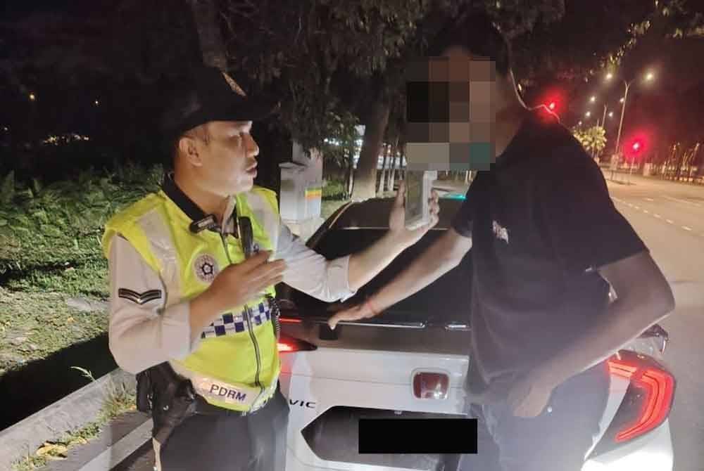 Anggota polis trafik menjalankan pemeriksaan terhadap seorang lelaki pada operasi khas berkenaan. Foto polis Johor