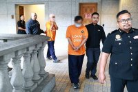 Pegawai SPRM mengiringi suspek yang terlibat dalam sindiket meluluskan pemeriksaan kenderaan berat di Mahkamah Majistret Putrajaya pada Selasa bagi mendapatkan permohonan reman.