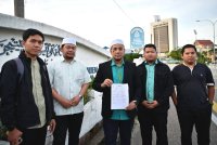 Muhammad Irsyad Syafiq (tengah) ketika selesai membuat laporan polis di IPD Kuala Terengganu pada petang Selasa.