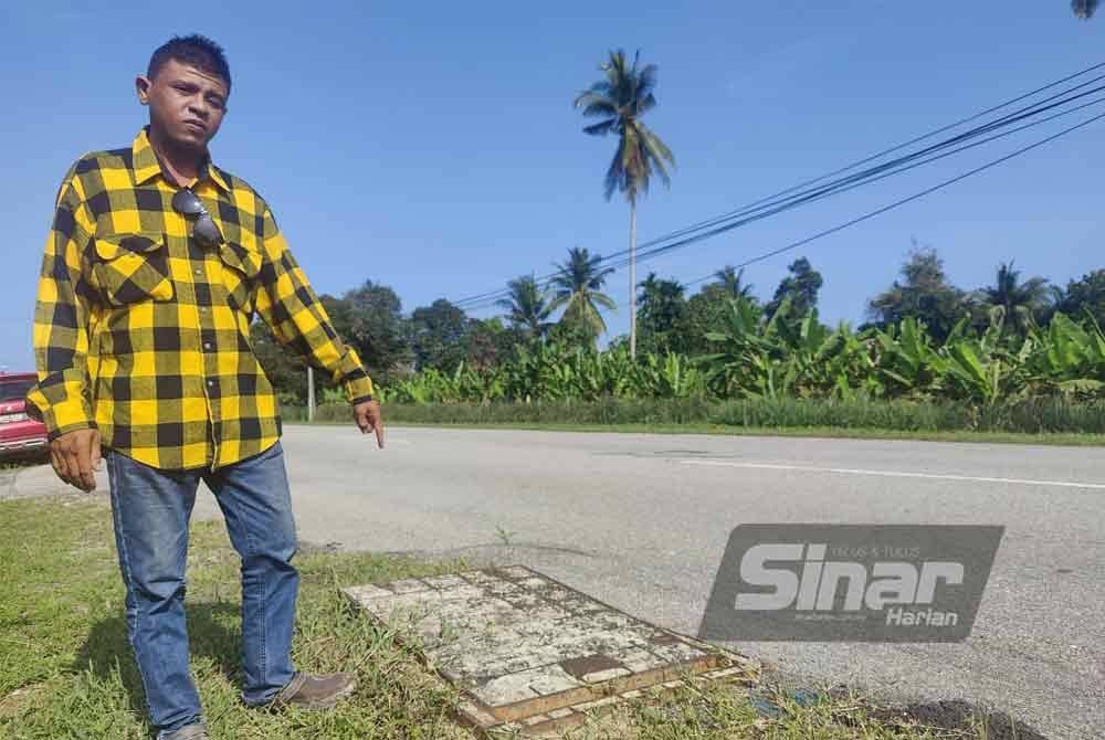 Zizi Azmi menunjukkan penutup lurang kabel terjongket yang mengundang risiko keselamatan kepada pengguna jalan raya.