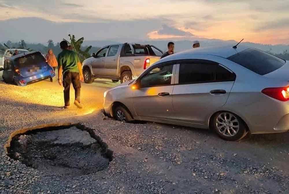 Dua buah kereta yang turut terbenam dalam lubang benam di Jalan Bendang Charuk, Changlun pada Selasa. Gambar ihsan pembaca