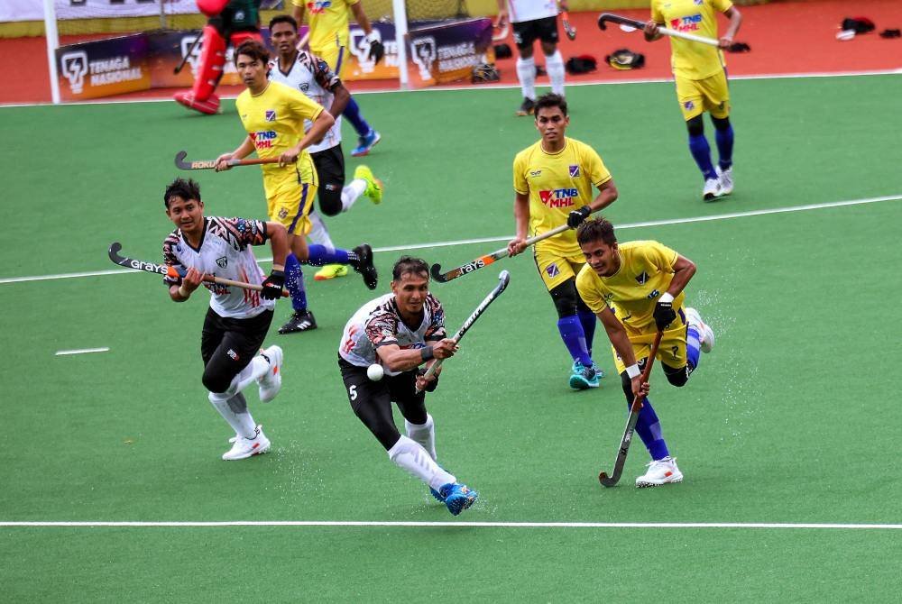 Pemain THT, Muhammad Firdaus Omar (tengah) dan pemain UiTM HA- KPT, Muhamad Hafiz Zainol (kanan) cuba mendapatkan bola pada saingan MHL di Stadium Hoki Majlis Bandaraya Kuala Terengganu Batu Buruk, hari ini. Foto Bernama