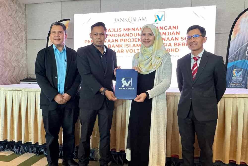 Mohd Muazzam (kanan) dan Timbalan Ketua Pegawai Eksekutif Kanan PDC, Datuk Mohammad Azhar Hamdan (kiri) menyaksikan upacara Memorandum Perjanjian Pembiayaan Projek Penjanaan Solar Antara Bank Islam Malaysia Berhad dan Solar Voltech Sdn Bhd yang diadakan di sebuah hotel di Bayan Lepas pada Selasa.