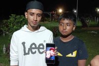 Mohd Danial Ikmal (kiri) dan Mohd Danial Irfan (kanan) menunjukkan gambar ibu bapa mereka yang maut dalam kemalangan di Thailand pada Isnin.