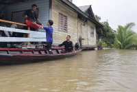 Sukarelawan menggunakan perahu untuk mengagihkan makanan kepada penduduk Kampung Hulu Serian yang dilanda banjir. Foto Bernama