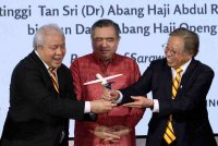 Abang Johari (kanan) dan Anthony Loke (tengah) melihat model pesawat selepas menyaksikan pertukaran perjanjian antara Kerajaan Sarawak dengan Malaysia Aviation Group pada Rabu. Foto Bernama