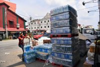 Pekerja pemborong barangan keperluan menyusun air mineral yang dijual ketika tinjauan di Pekan Teluk Intan, pada Khamis. Foto Bernama